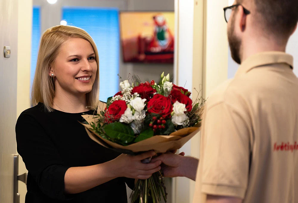Kurýr předává doručenou kytici obdarované